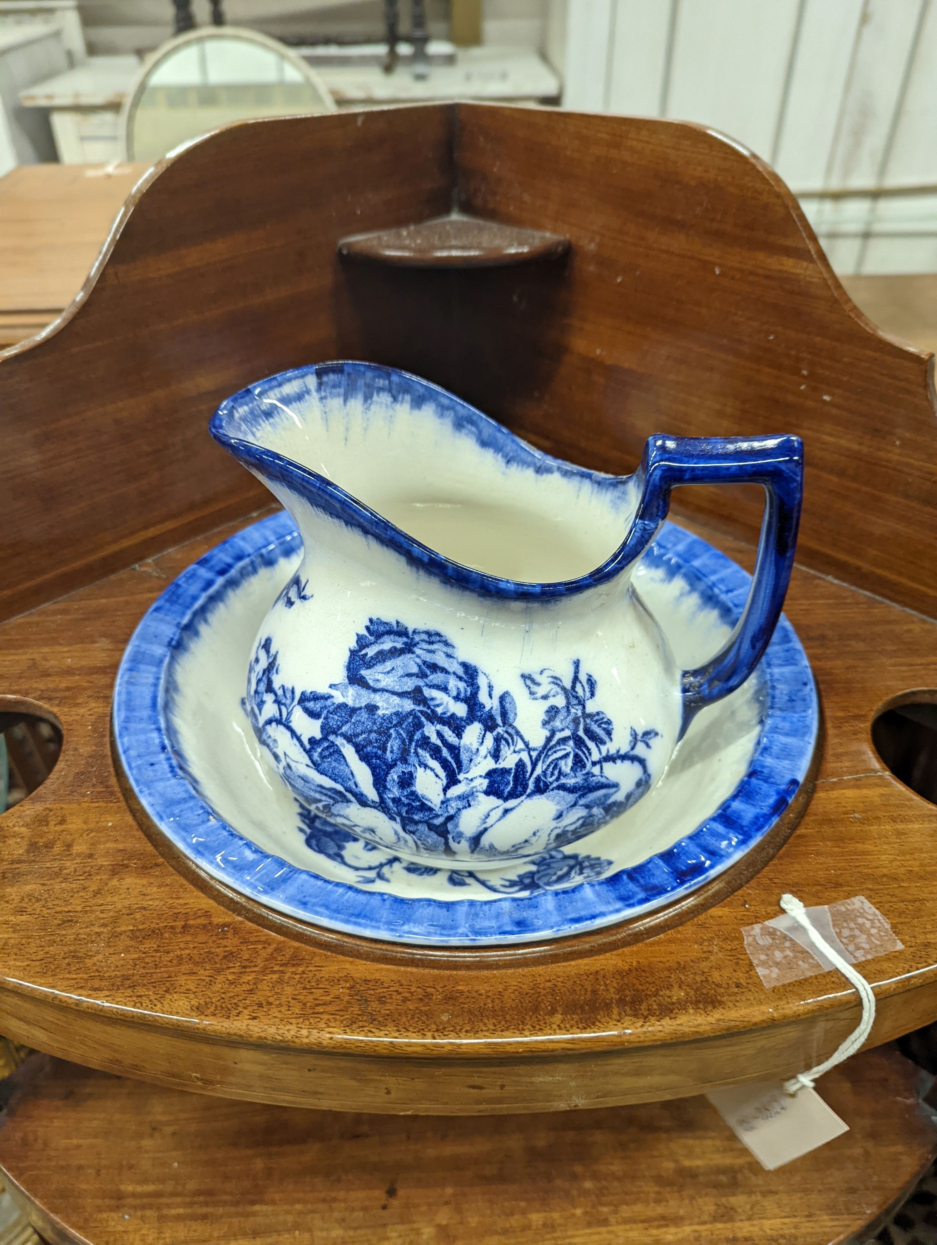 A George III mahogany bow front three tier corner washstand, width 58cm, depth 38cm, height 99cm with an associated jug and basin